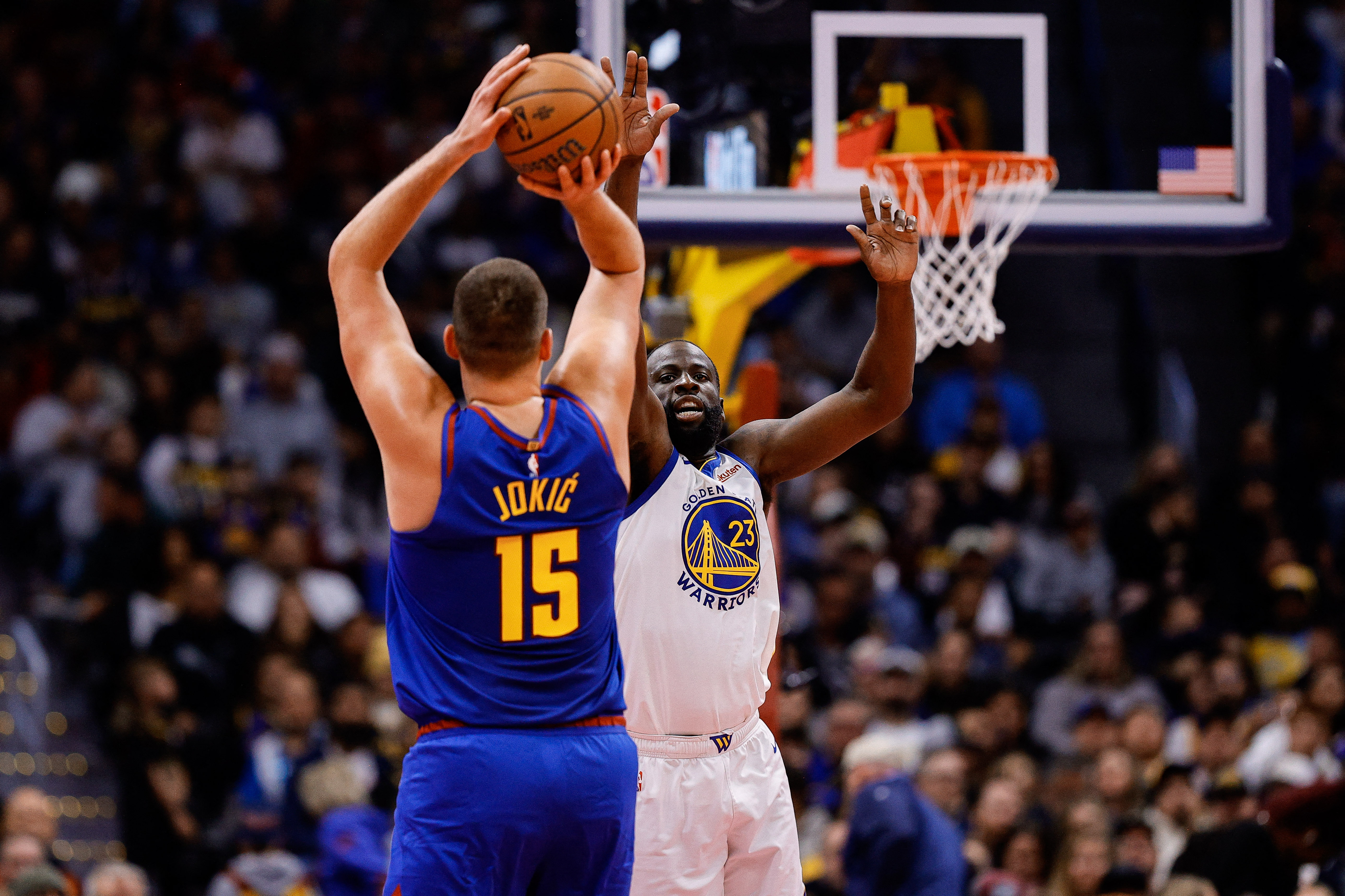 Denver Nuggets center Nikola Jokic attempts a shot under pressure from Golden State Warriors forward Draymond Green as we make our best Nuggets vs. Warriors predictions.