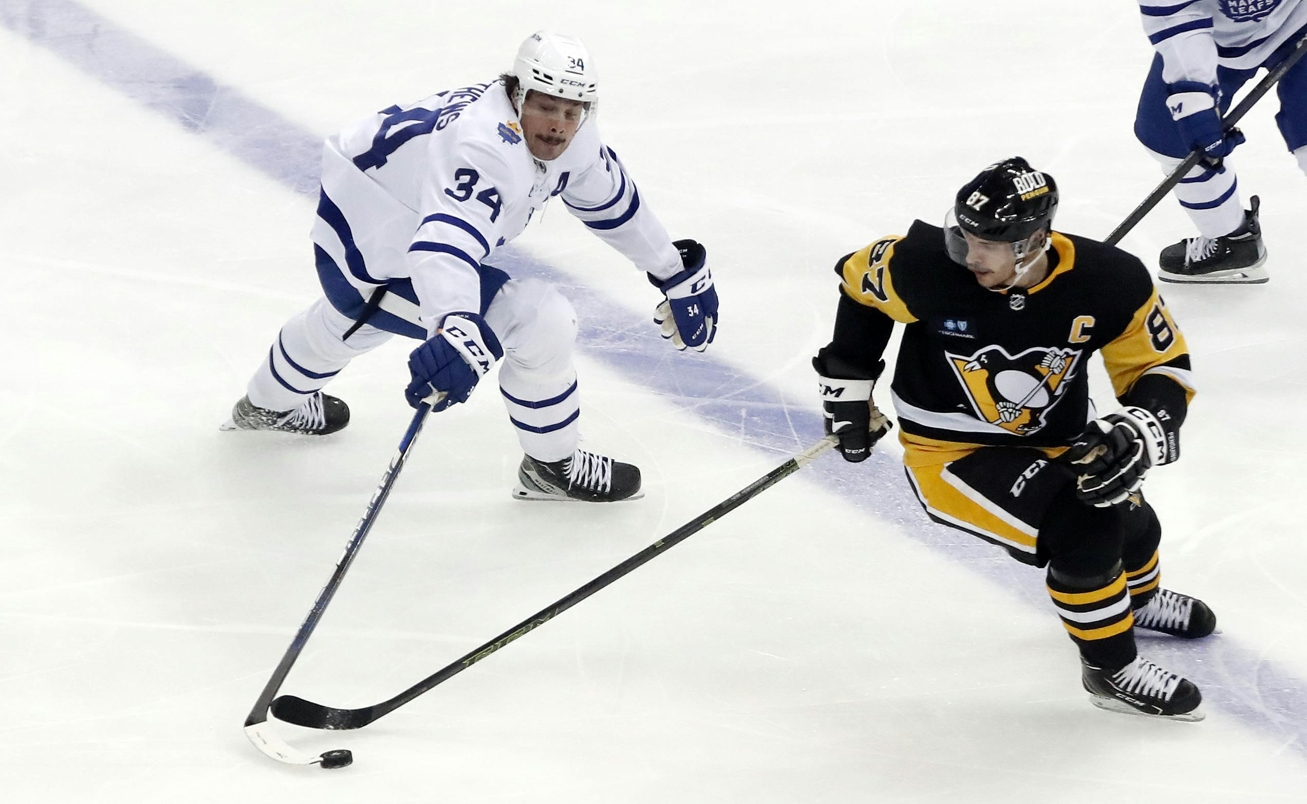 Toronto Maple Leafs center Auston Matthews and Pittsburgh Penguins center Sidney Crosby reach for the puck.<br>