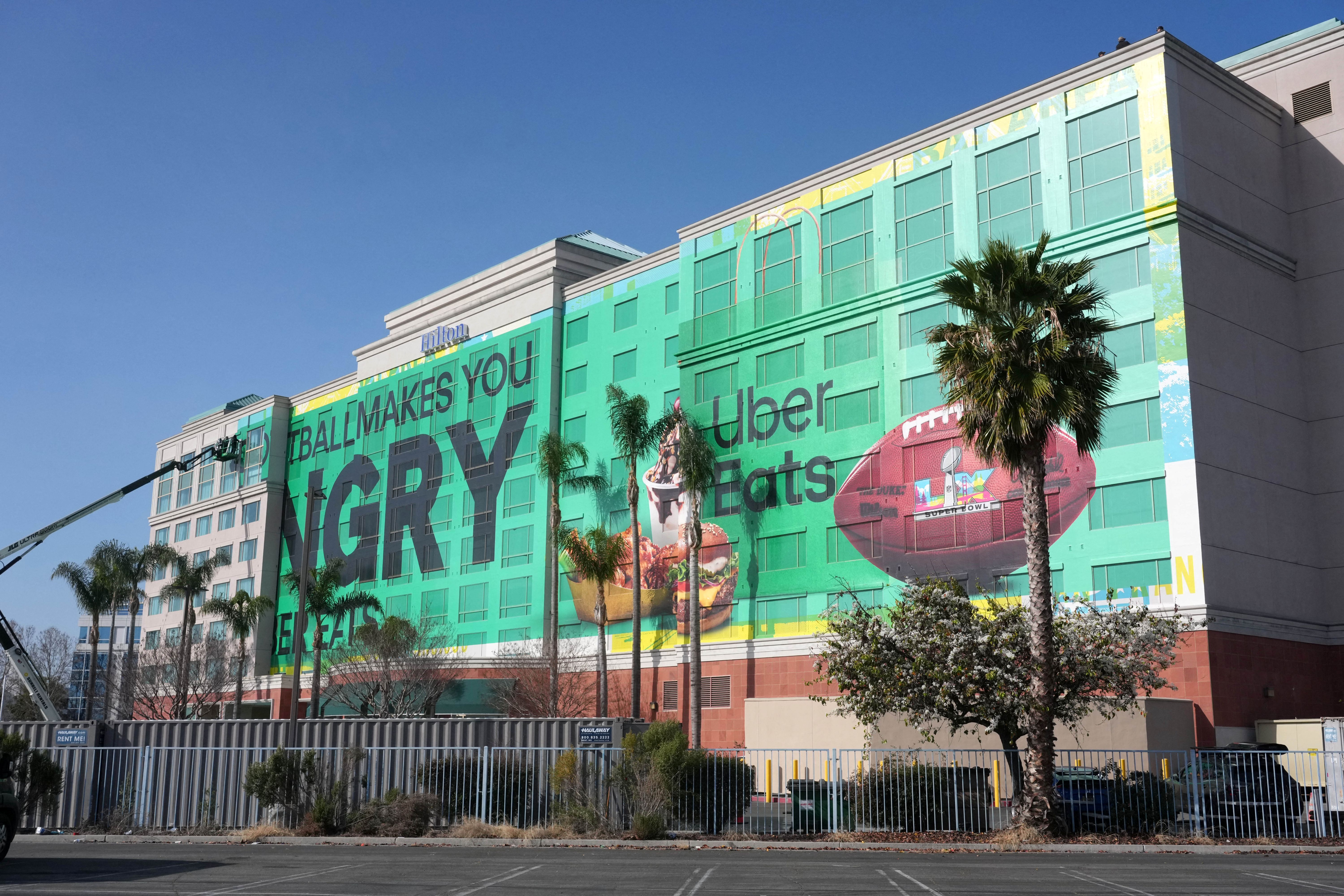 Workers erect a Super Bowl advertisement as we look at the prediction markets for Super Bowl commercials.