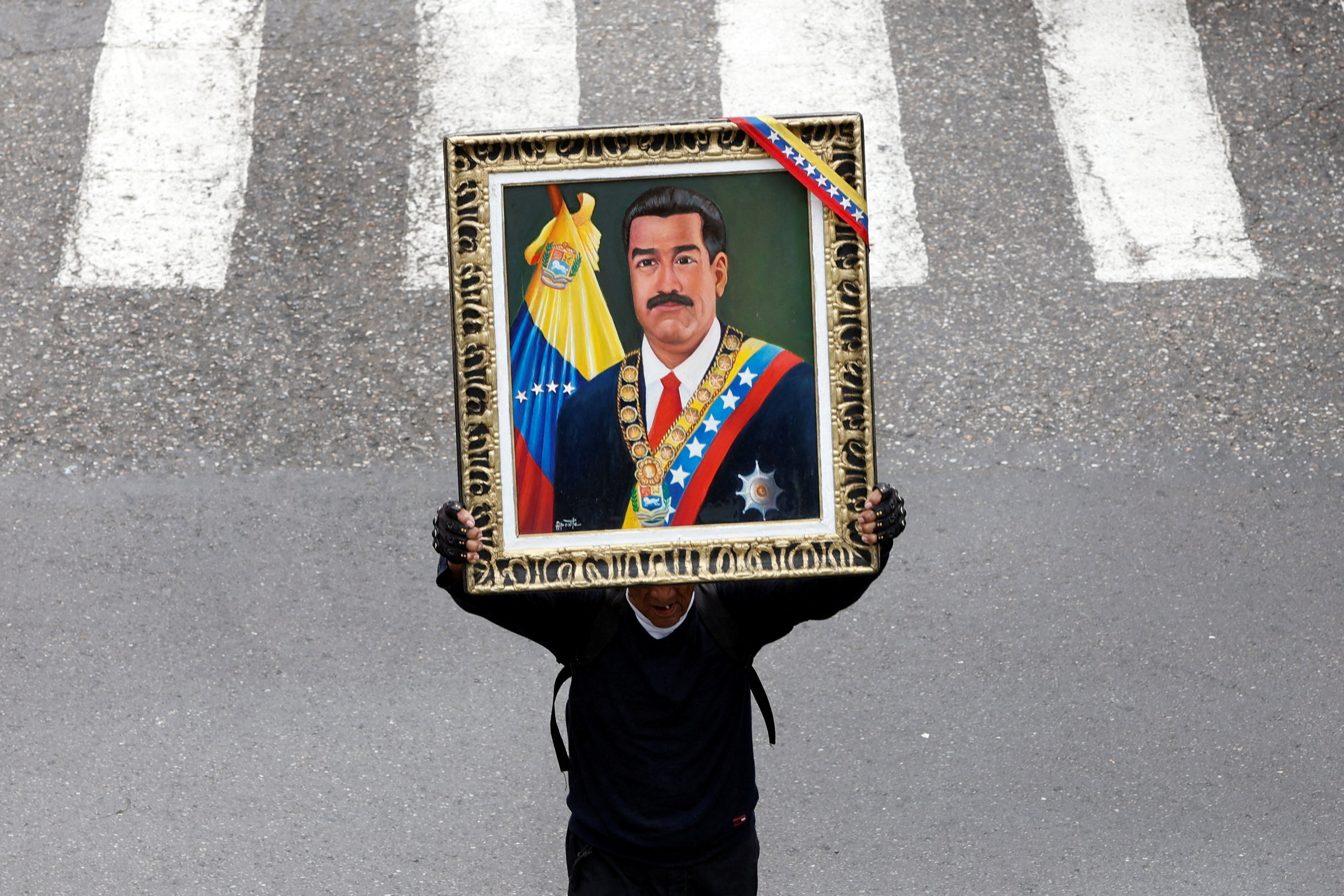 A demonstrator holds a painting of ousted President Nicolas Maduro as we look at the soldier charged for betting on Polymarket about his ousting.
