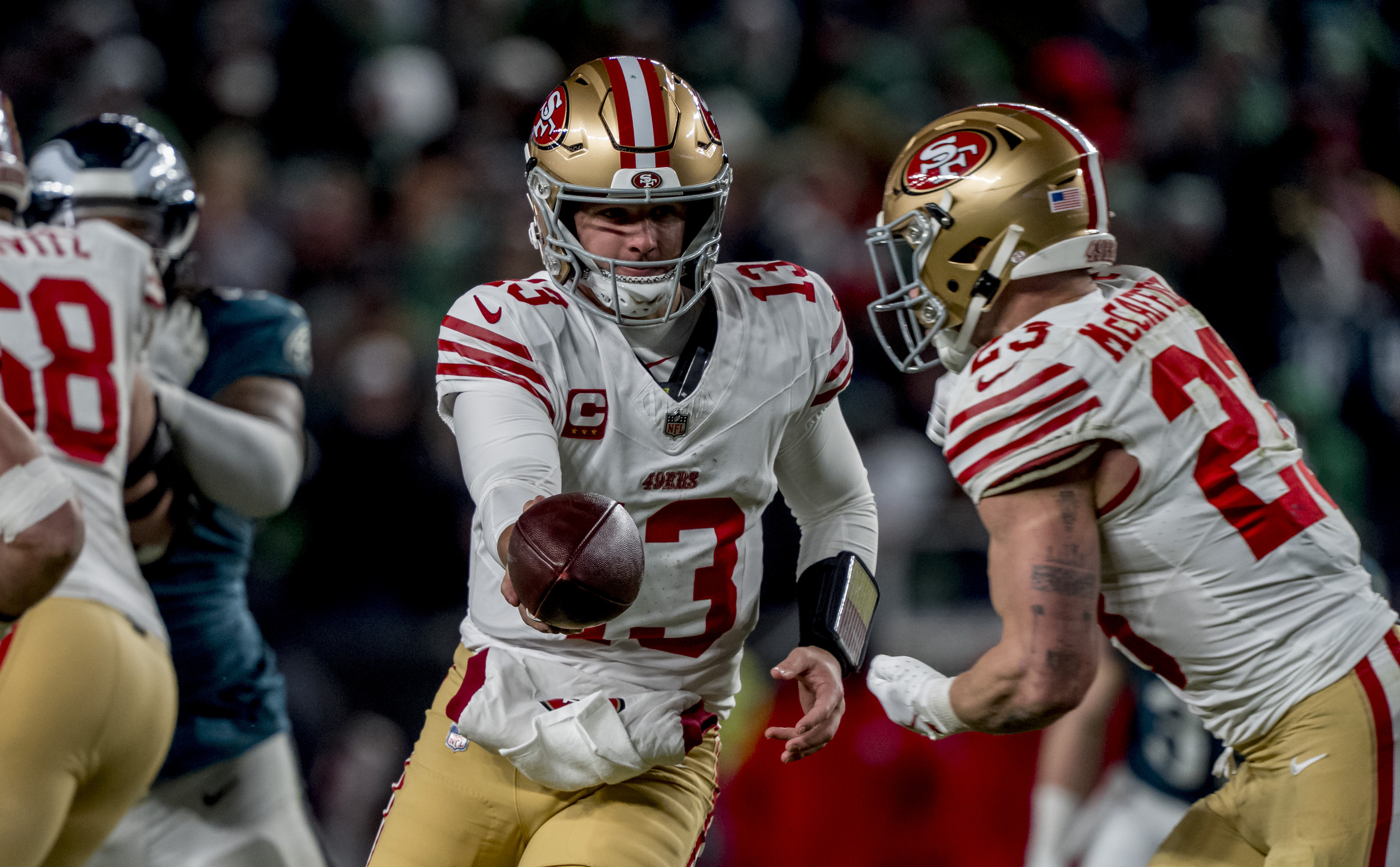 San Francisco 49ers quarterback Brock Purdy (13) hands the ball off to running back Christian McCaffrey (23) as we break down our 49ers vs. Seahawks expert picks for Divisional Round.