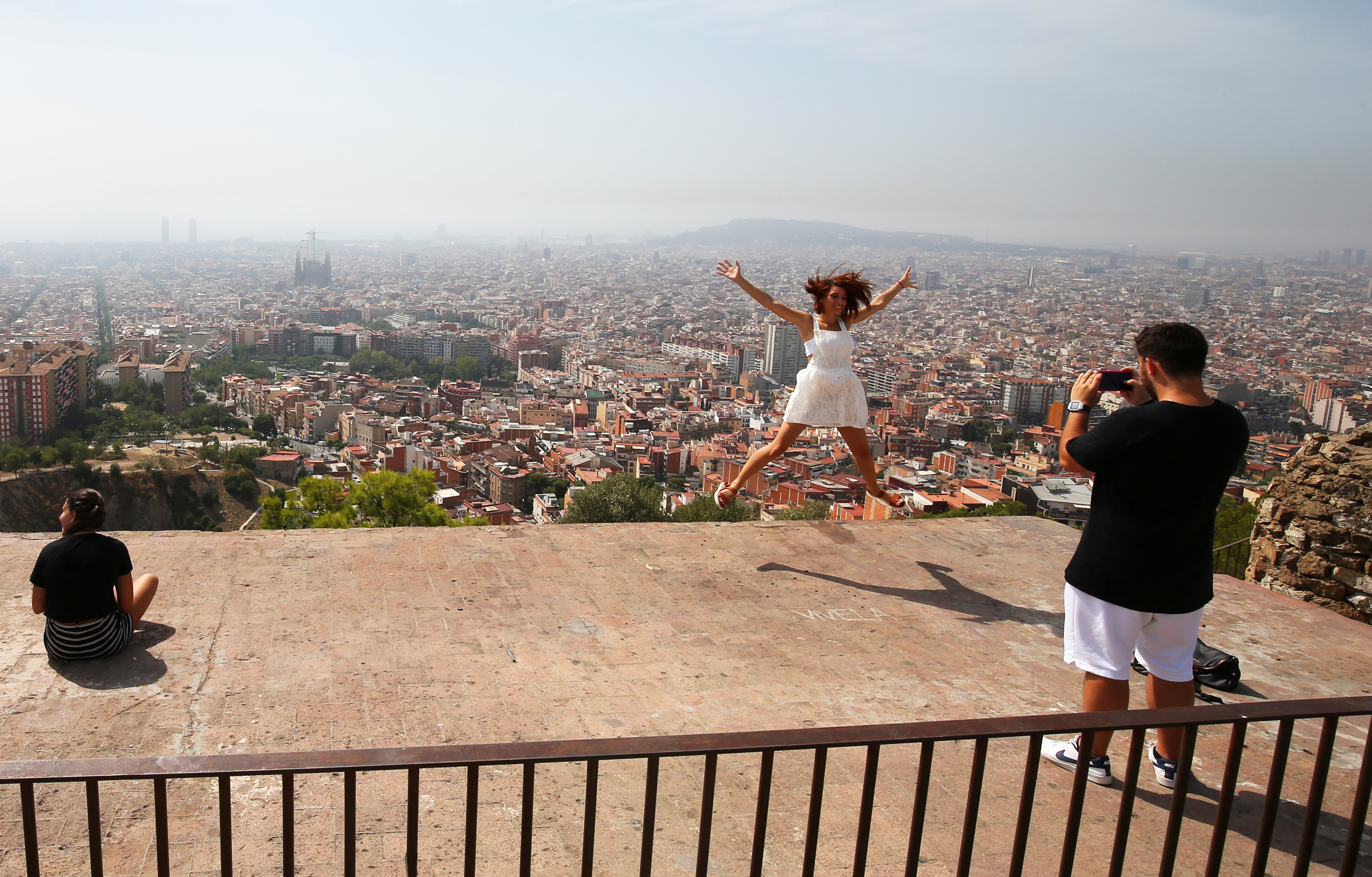  A tourist leaps in the air with a backdrop of the skyline of Barcelona, Spain, as we break down our 10 cities we'd like to see host the Super Bowl.