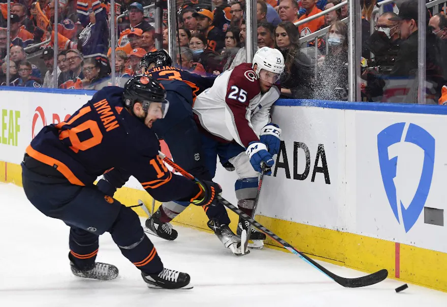 Zach Hyman of the Edmonton Oilers controls the puck as Logan O'Connor of the Colorado Avalanche is checked into the boards during Game Four of the Western Conference Final at Rogers Place on June 06, 2022 in Edmonton, Alberta.