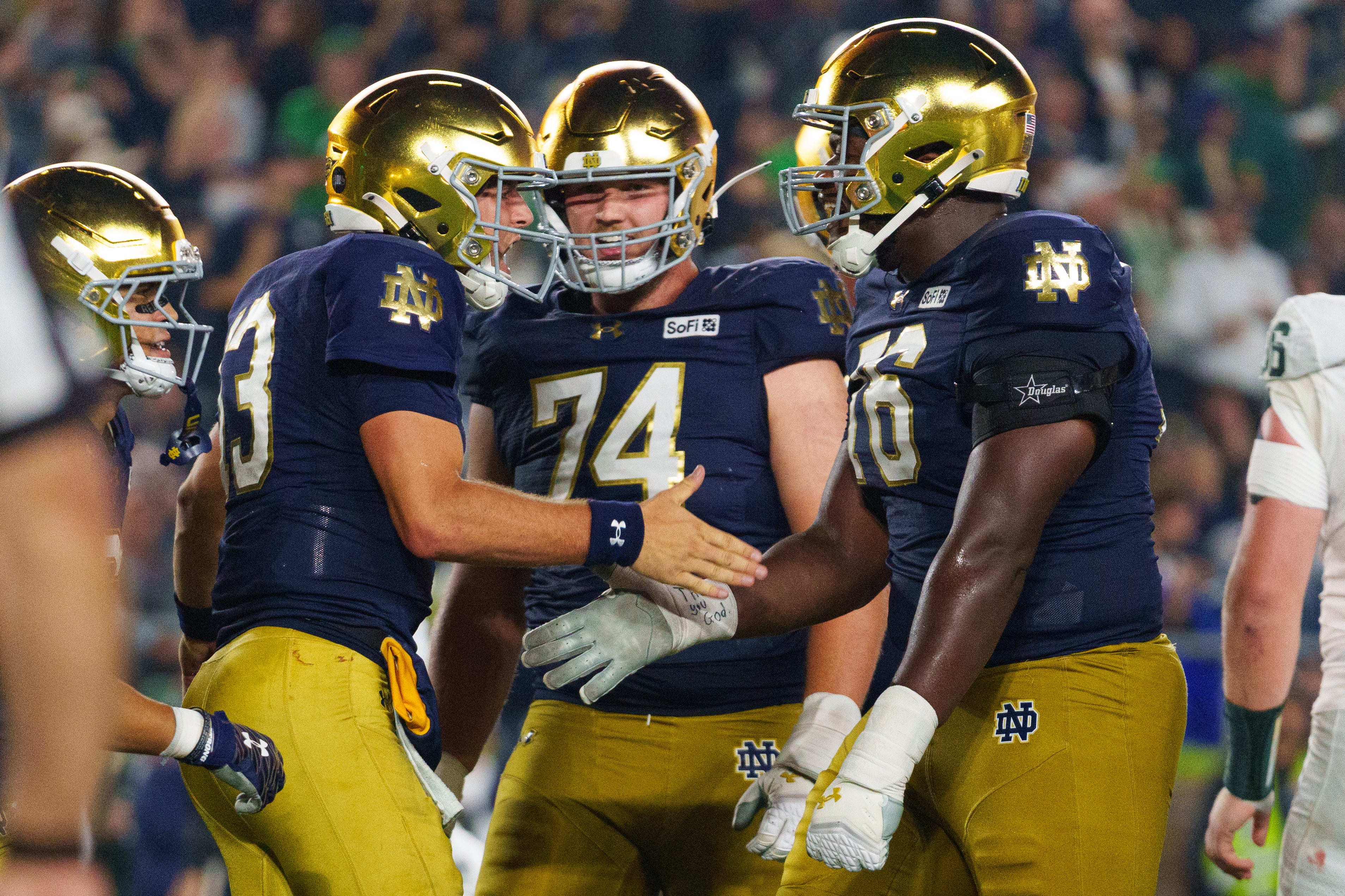 Notre Dame quarterback CJ Carr and teammates celebrate as we make our best Notre Dame vs. Purdue prediction.
