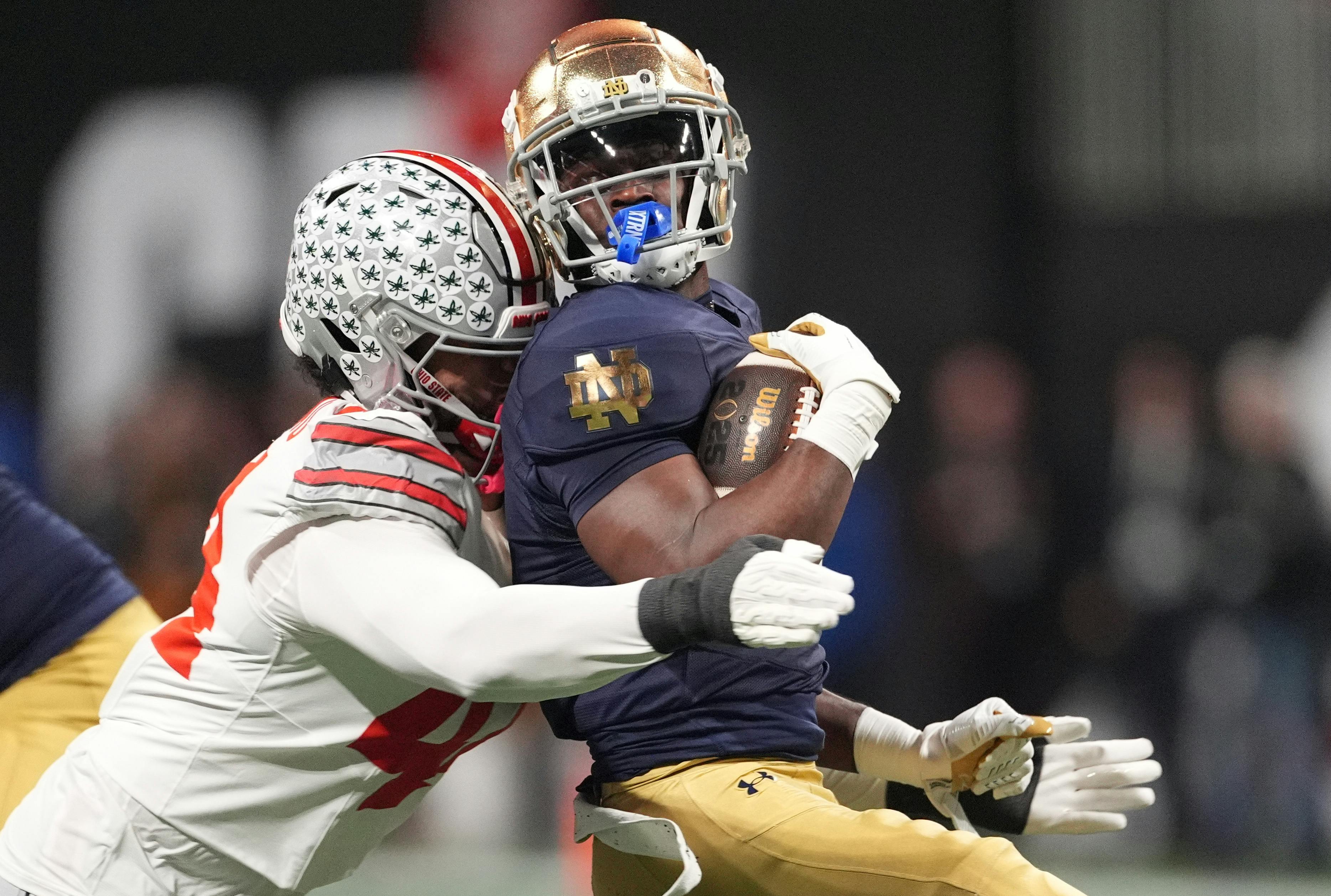 Notre Dame Fighting Irish running back Jeremiyah Love is tackled by Ohio State Buckeyes defensive end JT Tuimoloau as we analyze the 2026 college football national championship odds.