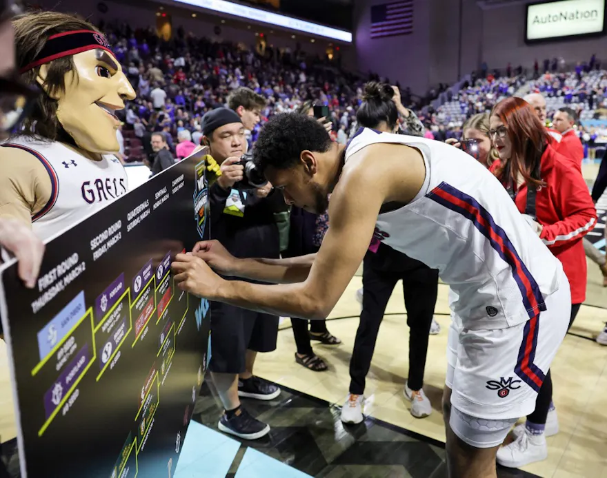 Josh Jefferson of the Saint Mary's Gaels puts a sticker on a tournament bracket board as we look at our March Madness bracket predictions.