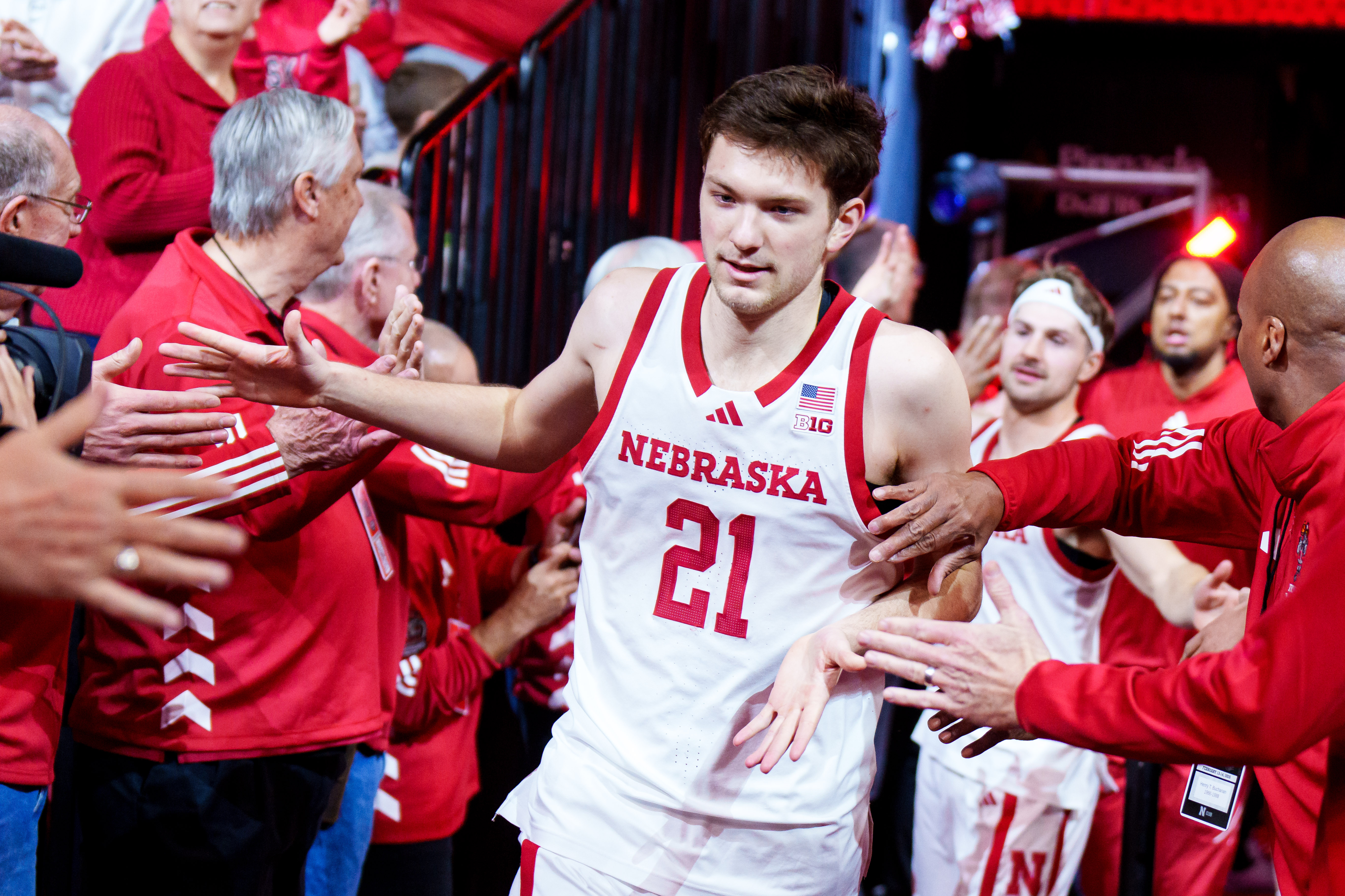 Nebraska forward Pryce Sandfort (21) runs onto the court while being greeted by alumni players as we look at our Troy vs. Nebraska prediction and parlay today