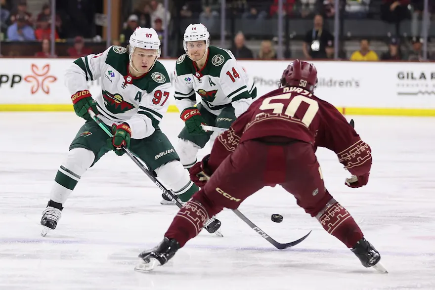 Kirill Kaprizov of the Minnesota Wild skates with the puck against Sean Durzi of the Arizona Coyotes. Caesars Sportsbook and the NHL announced an enhanced and extended partnership deal.