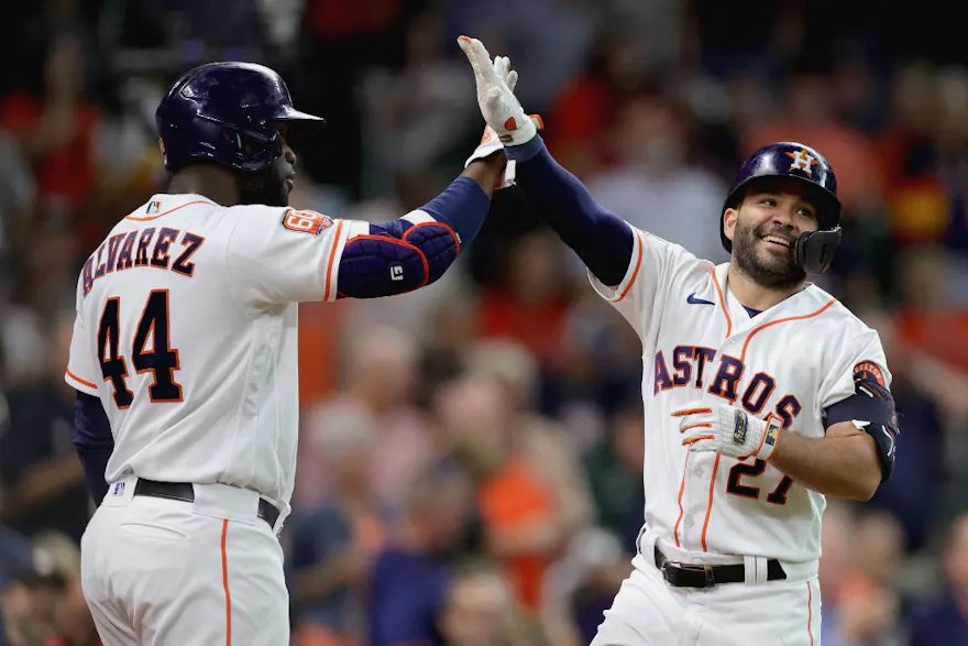 Jose Altuve of the Houston Astros high fives Yordan Alvarez after hitting a solo home run during the first inning against the Minnesota Twins at Minute Maid Park.