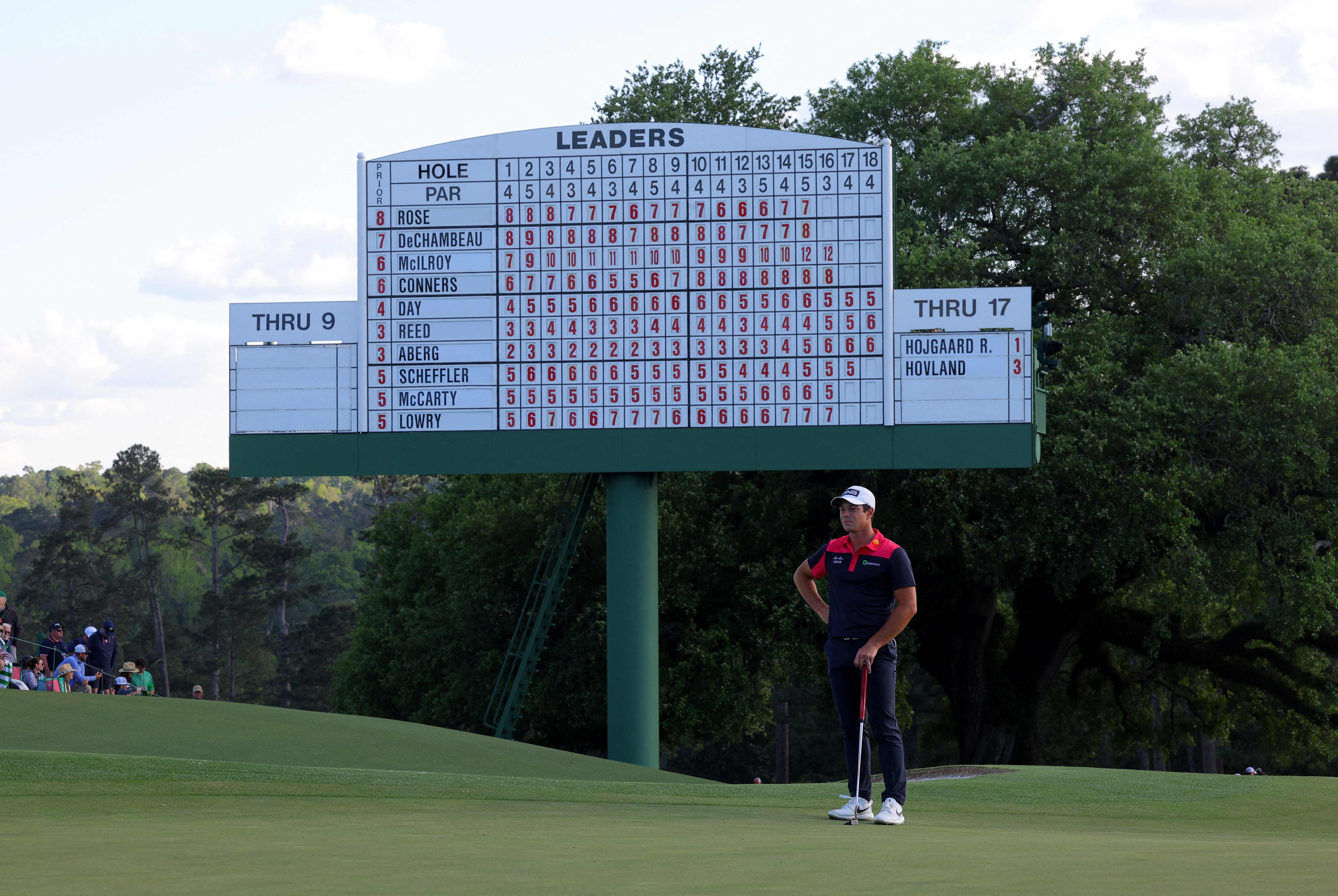 Viktor Hovland, one of my Masters long shots, stands on the green in front of the scoreboard on the 18th hole