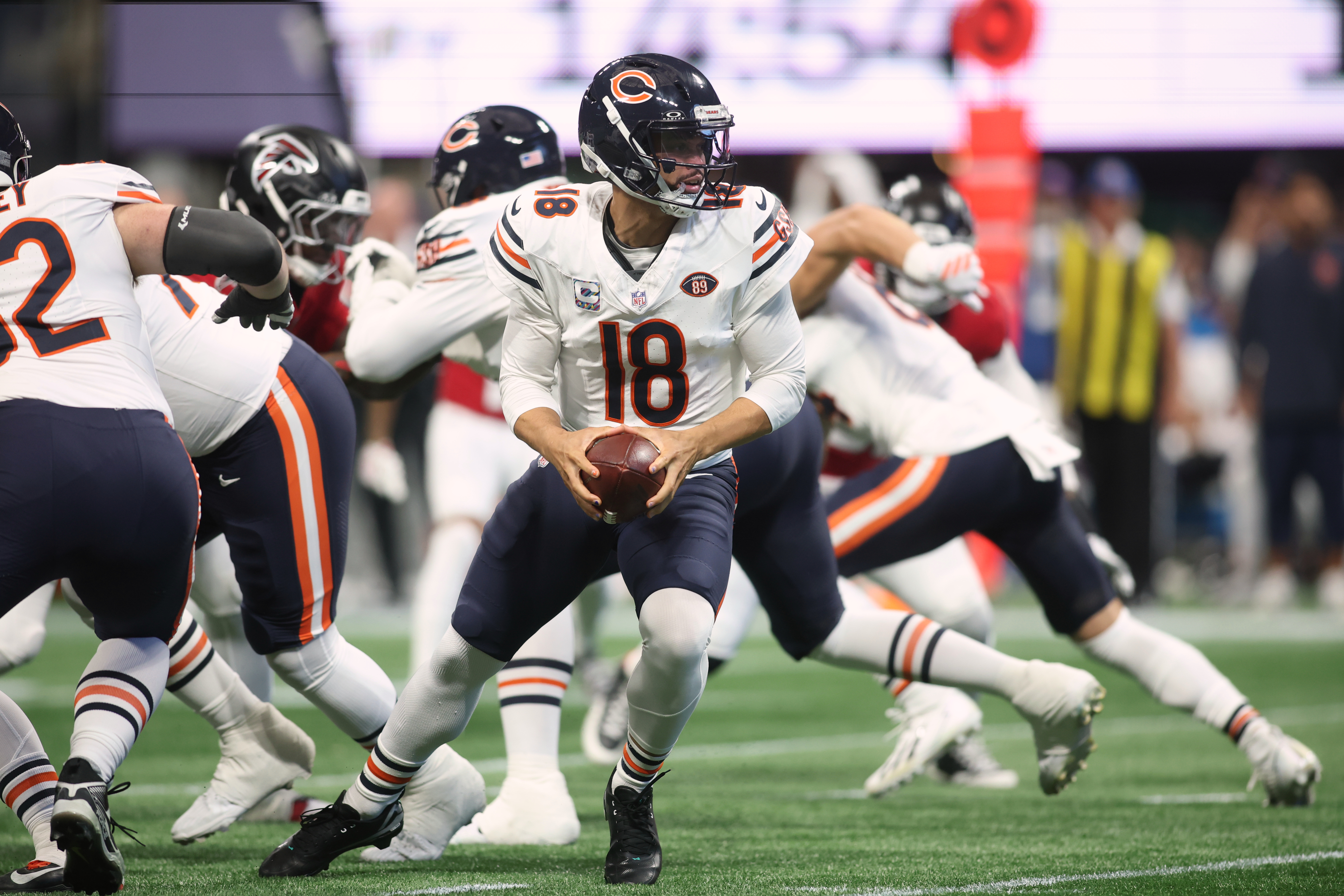 Chicago Bears quarterback Caleb Williams rolls out to throw the ball as we make our best Patriots vs. Bears expert picks.